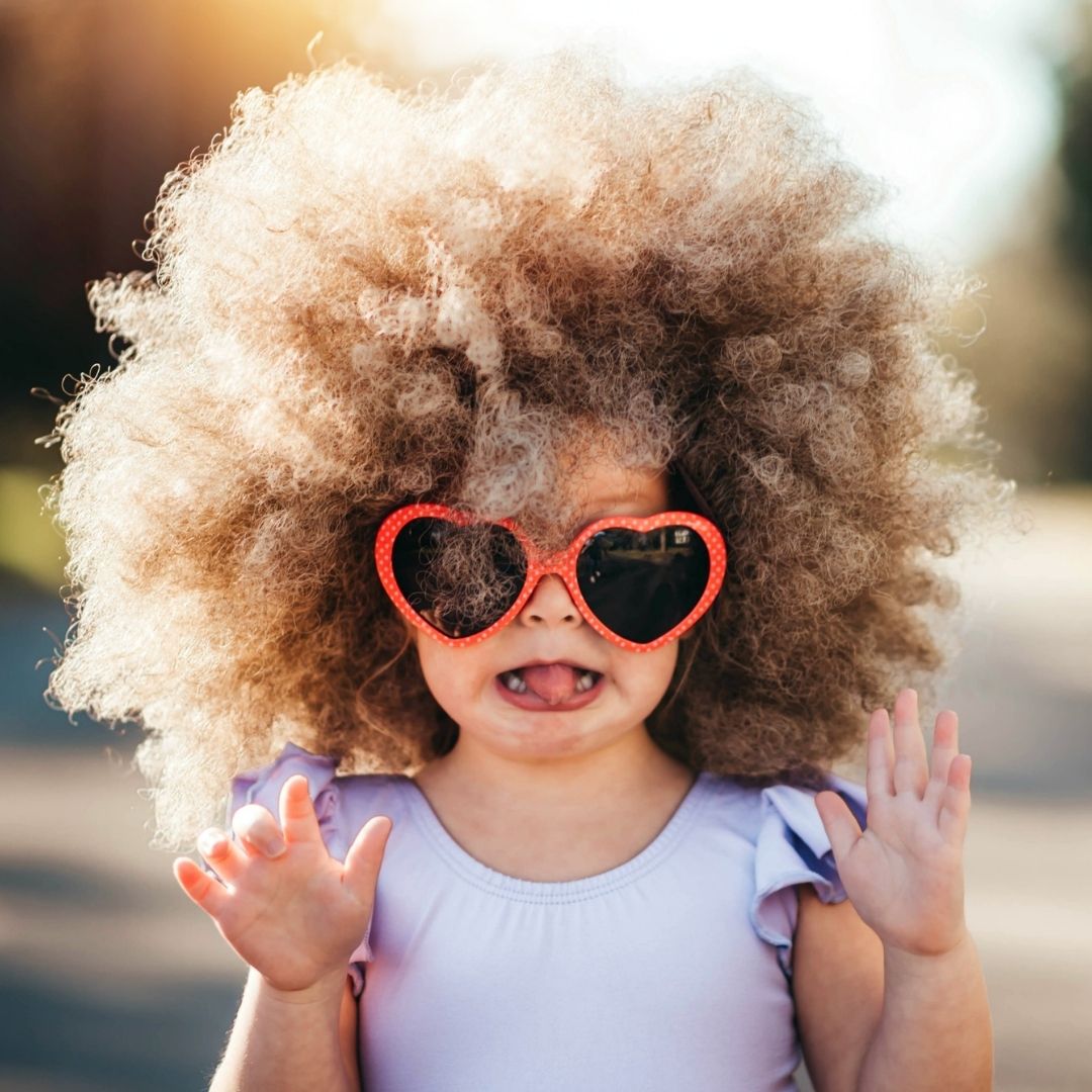 Litlle girl with heart shaped sunglasses and an afro (curly hair)